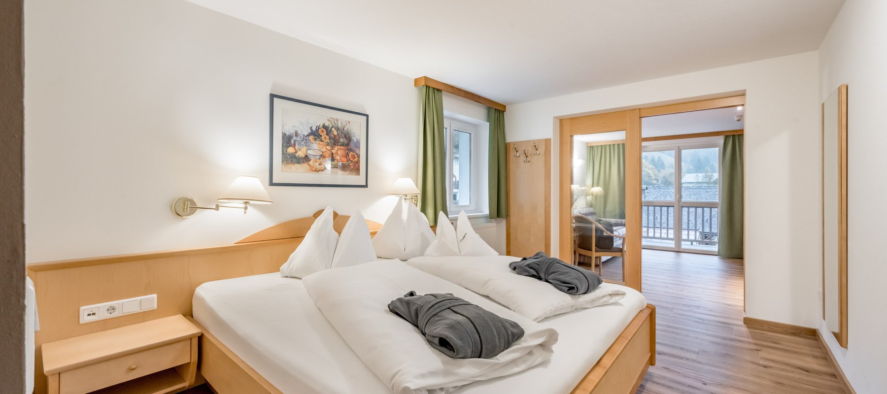 Schlafzimmer mit Doppelbett und angrenzendem Wohnraum mit Balkon