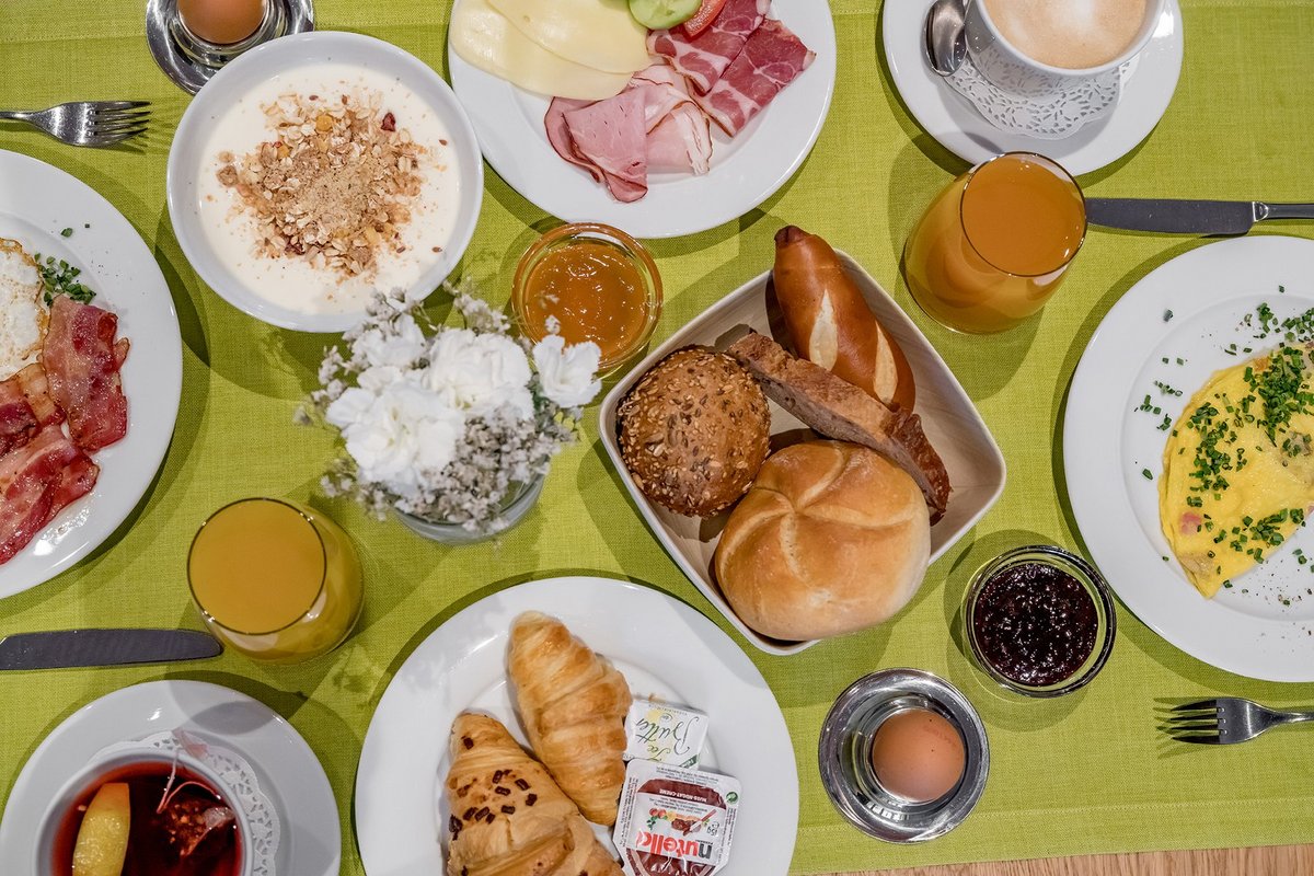 Frühstückstisch frischem Brot, Aufschnitt, Ei, Speck, Marmelade, Kaffee, Fruchtsaft und Croissants