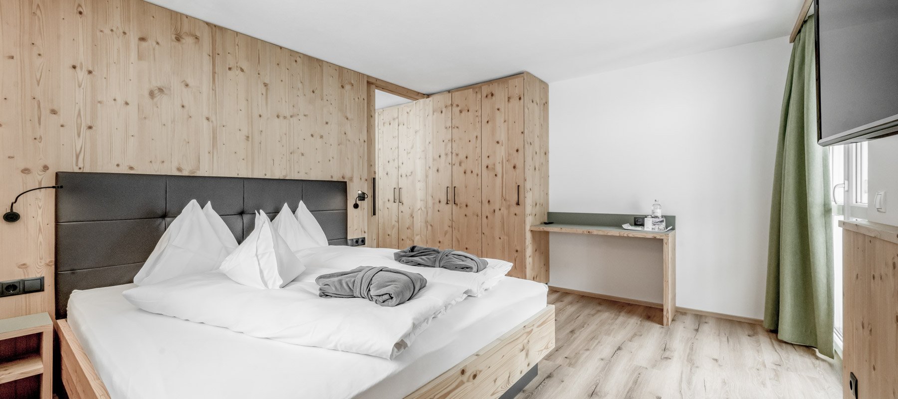 Schlafzimmer mit hochwertiger Holzeinrichtung und Fernseher