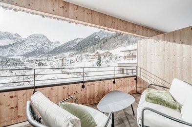 Gemütlicher Hotelbalkon mit Blick auf verschneite Dächer und Berglandschaft