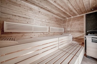 Liegeflächen aus Holz in einer Sauna mit Elektroofen und heißen Steinen