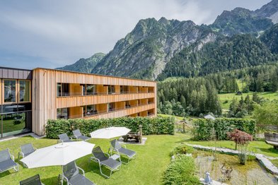 Hotel mit Garten, Sonnenliegen mit Schirmen und Teich in den Bergen