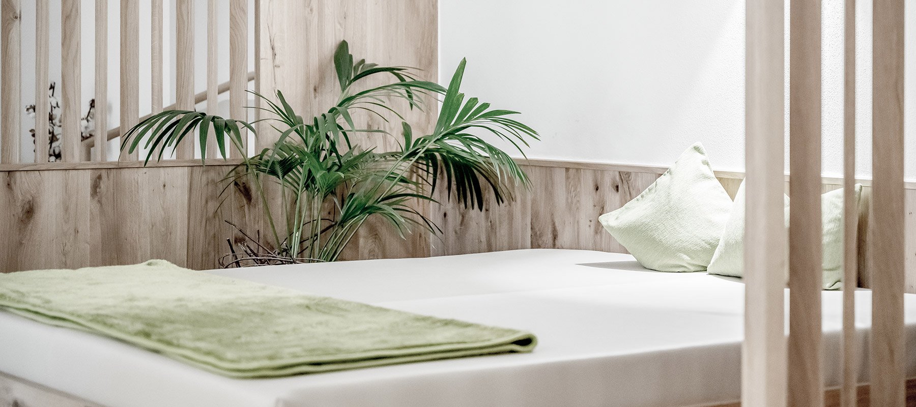 Entspannungsliege im Ruheraum mit grünen Kissen und Decke