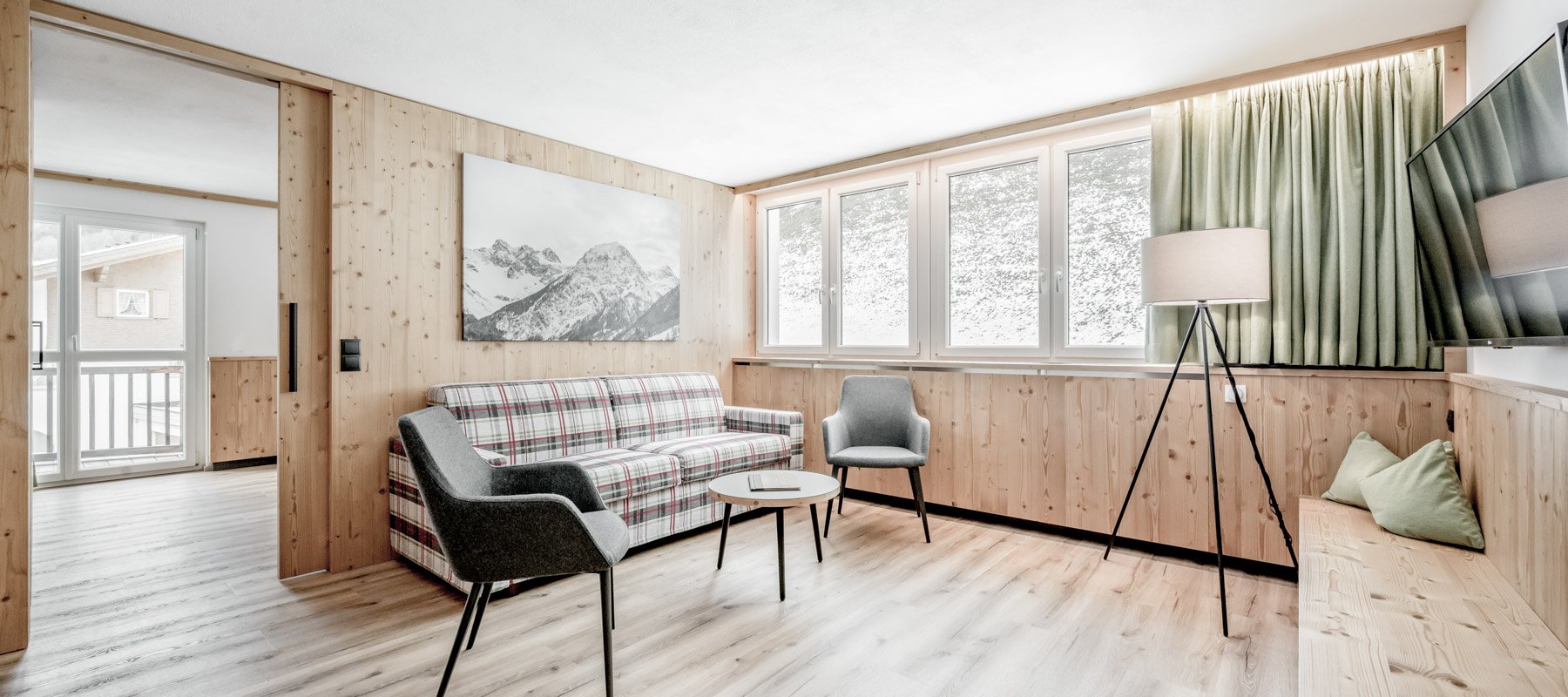 Wohnraum mit viel Holz, gemütlichem Sofa und TV