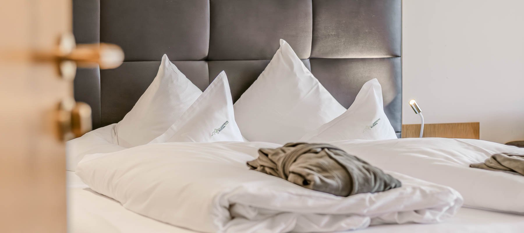 Modernes Schlafzimmer mit großem Bett, weißen Kissen und gepolstertem Kopfteil