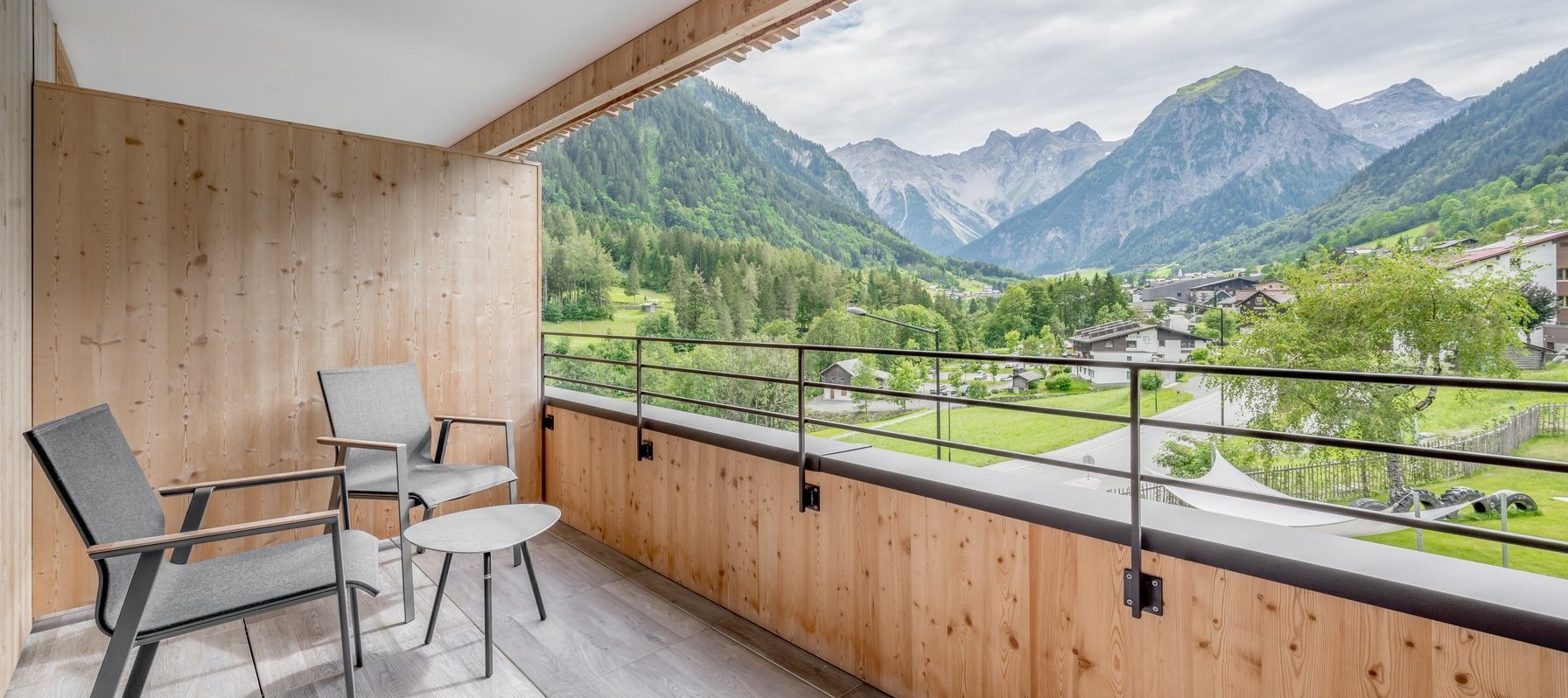 Großer moderner Balkon mit Stühlen, Tisch und Ausblick auf das Bergpanorama im Sommer 