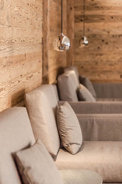 Gemütliche Sitznische mit Polstersesseln und Pendelleuchten vor Holzverkleidung